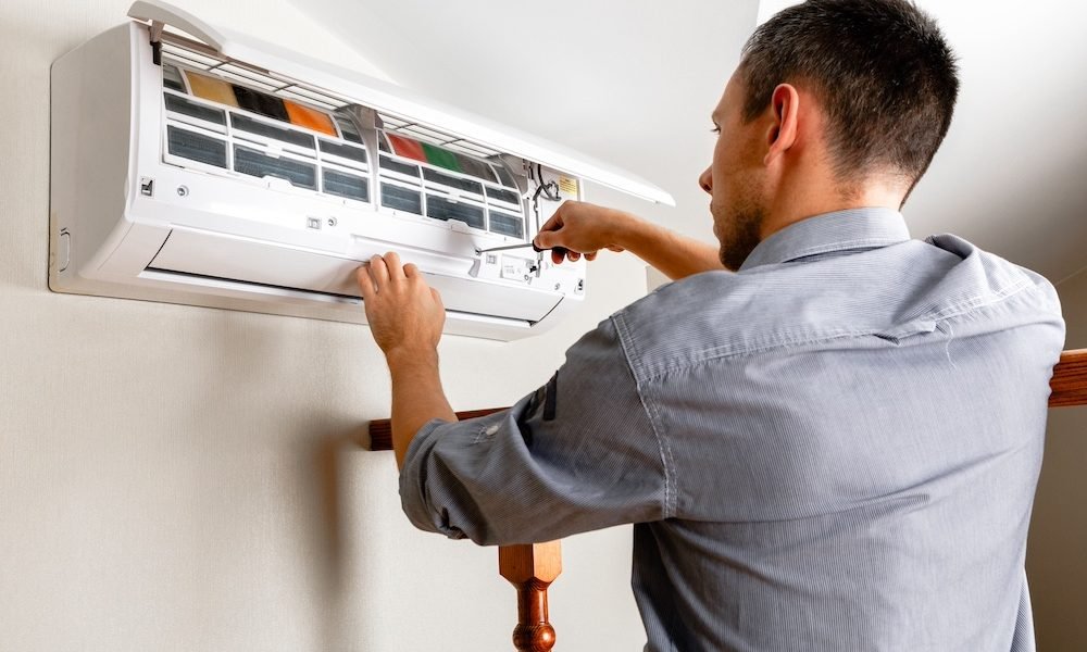 Male technician cleaning air conditioner indoors
